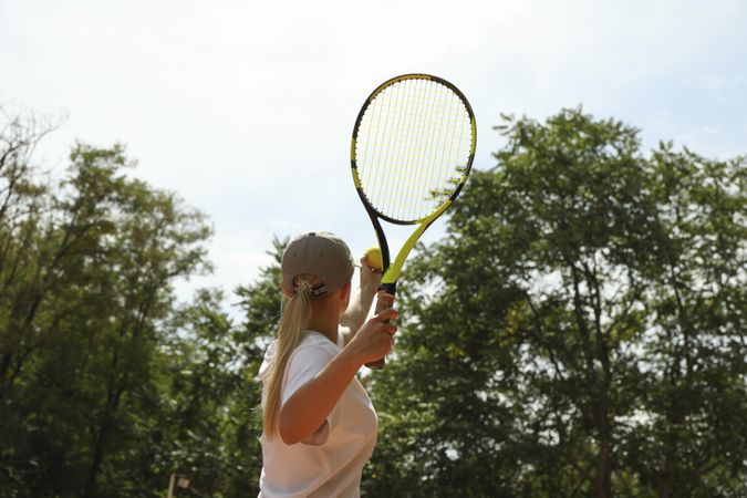 Young woman in white t-shirt serve the tennis ball