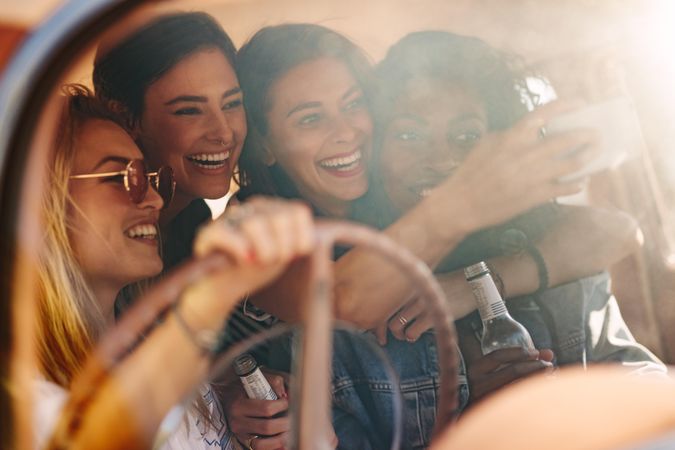 Group of young friends taking selfie in the car