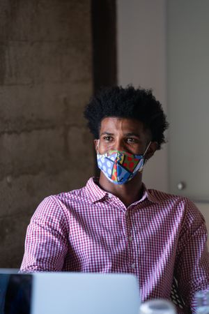 Man in colorful face mask talking with colleague in a bright modern office