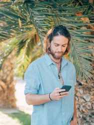 Young hipster man texting in jungle