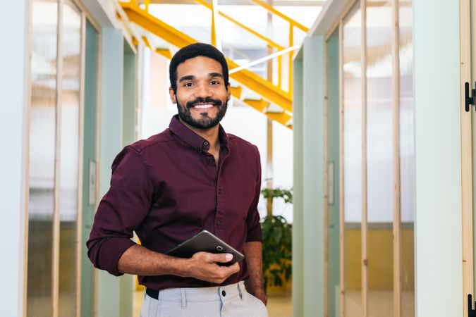 Portrait of smiling man in shirt holding tablet in modern office