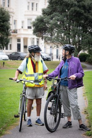 Two older people standing and talking with bikes