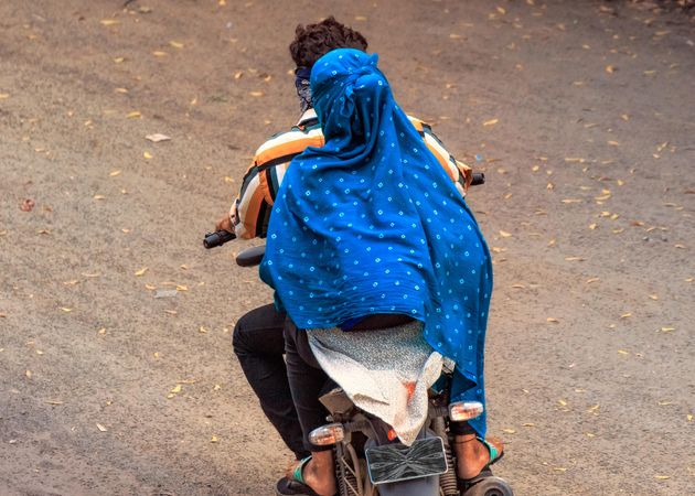 Back view of man and woman wearing the hijab riding a motorbike in India