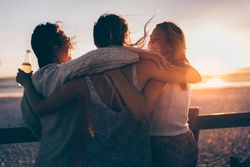 Group of friends embracing on the beach at sunset