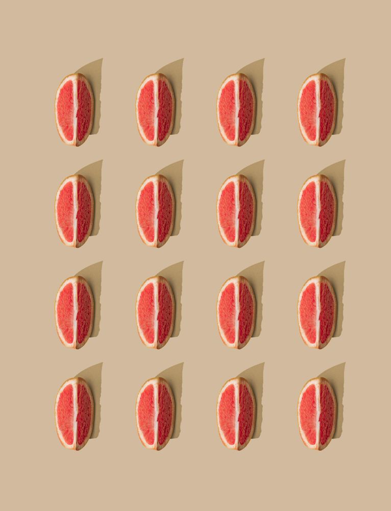 Pattern of grapefruit slices and pastel sand background