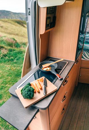 Vegetables being cooked on stove in motorhome vehicle, vertical