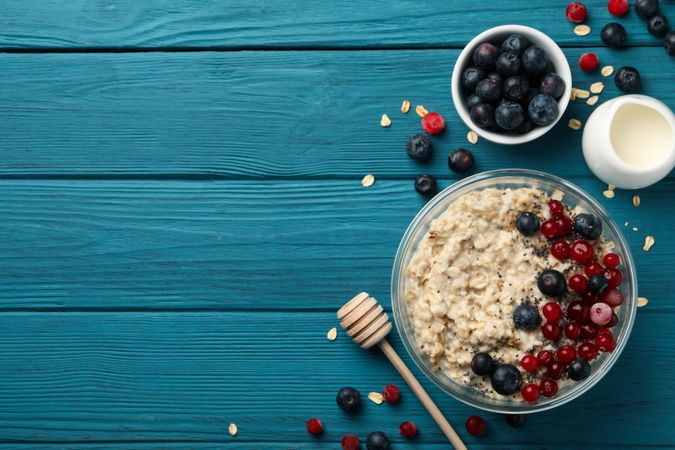 Bowl with oatmeal porridge and fruits on wooden background. Cooking breakfast