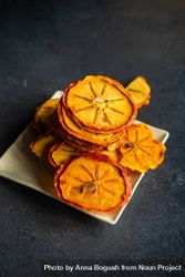 Dried persimmon fruits piled on square plate 426owx