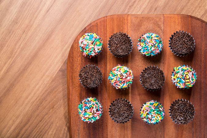 Top view of chocolate truffles with sprinkles presented on a wooden board