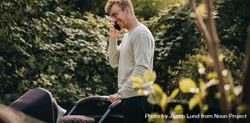 Man talking on mobile phone and pushing stroller outdoors 5p9yv4