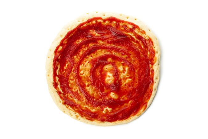 Rolled out pizza dough with sauce isolated on blank background