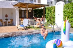 Active child jumping into swimming pool near mom relaxing on sun