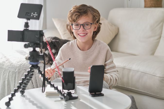 Portrait of boy recording video in living room at home