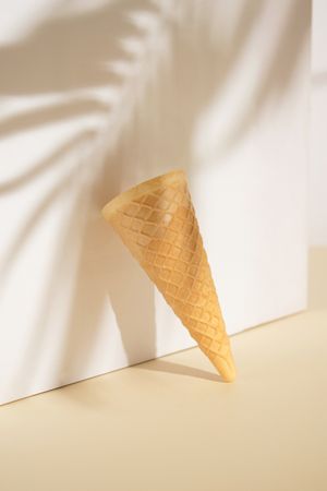 Ice cream cone standing against the wall making shadow