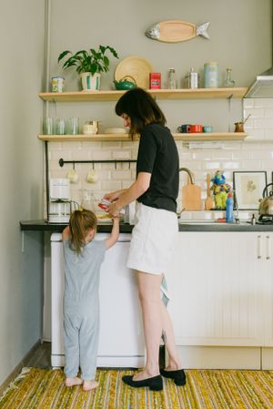 Back view of mother and young girl standing in the kitchen