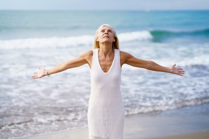 Older woman opening her arms on a tropical beach