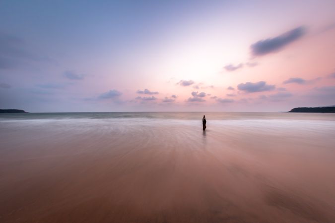 Silhouette of person walking on beach during sunset