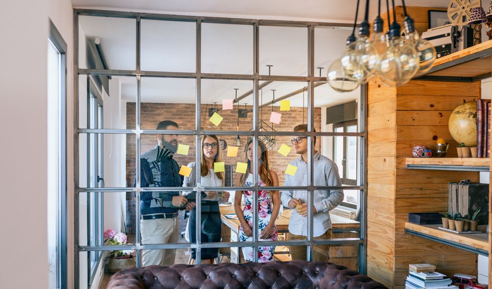 Business people in a work meeting placing sticky notes on the wall