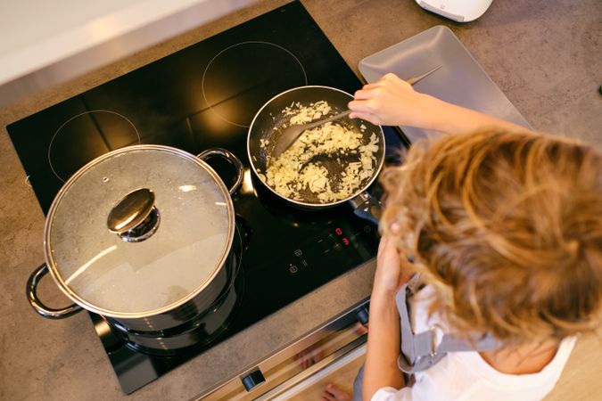 Unrecognizable person stirring onion in pan on stove top