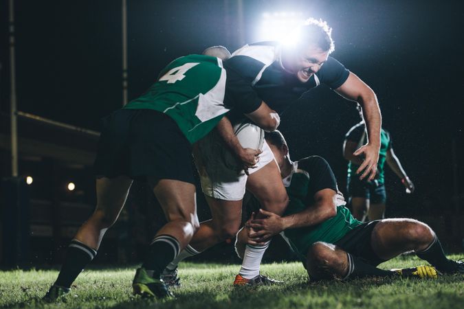 Rugby team players competing in game under lights