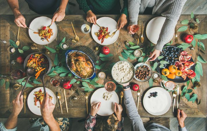 Group, with cat, serving themselves from festive table with roasted chicken and pomegranates