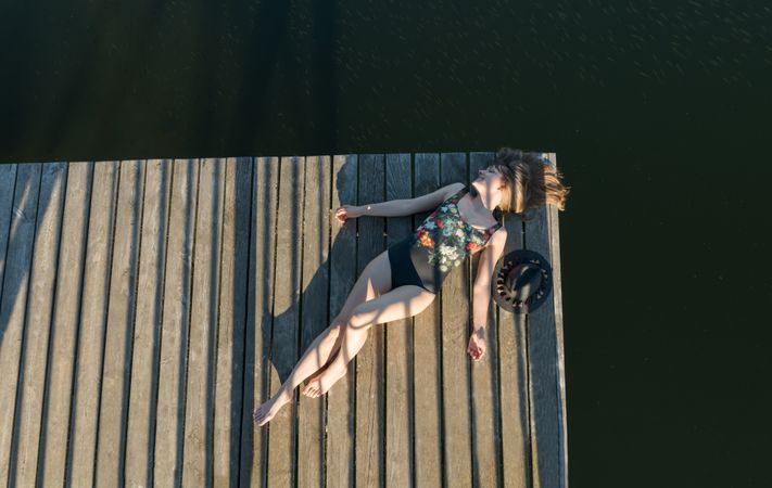 Young female lying down on pier on nature