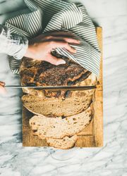 Top view of person slicing fresh homemade bread