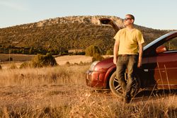 Man leaning in broken car in countryside