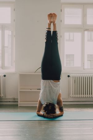 Fit woman practicing yoga pose and standing on head at home