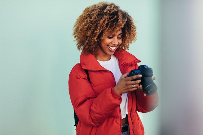 Woman smiling while looking at pictures on back of dslr camera
