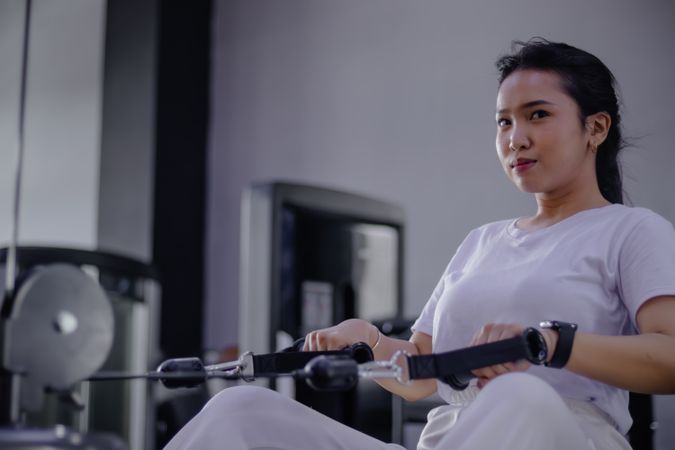 Focused woman training on rowing machine in gym for fitness goal