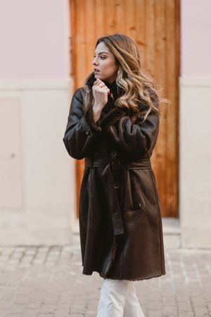 Stylish woman standing near brown door