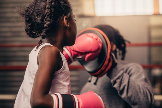 Girl wearing boxing gloves training with her coach
