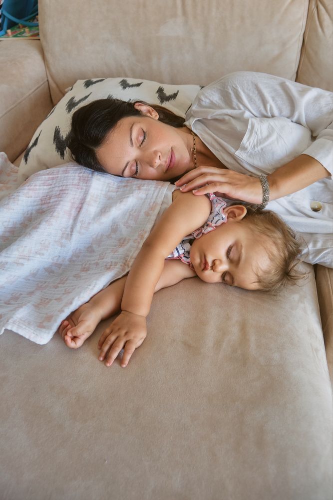 Vertical photo of a mother and toddler sleeping together on the