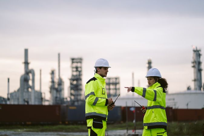 Two industrial workers observing and discussing at refinery factory