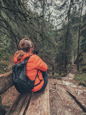 Tourist resting with smartphone on hiking path