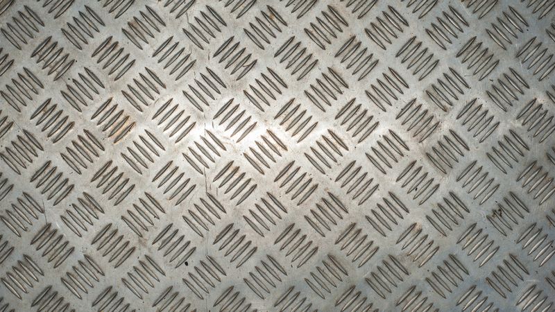 Silver metal floor plate with diamond pattern and polished steel texture