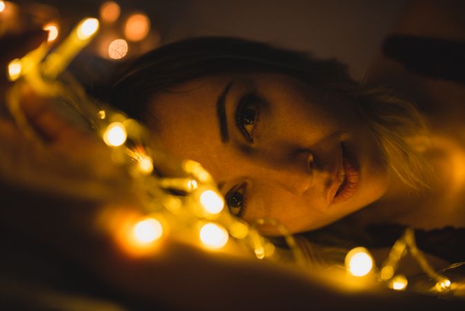 Woman lying surrounded by light garland