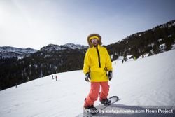 Man in yellow parka and goggles with snowboard 5oPjQ4