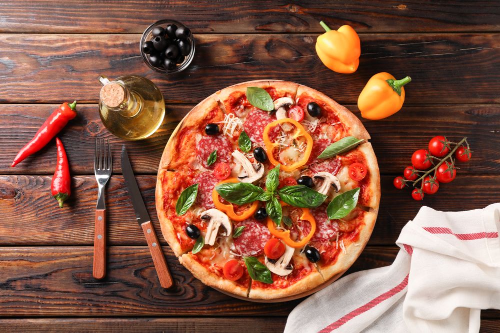 Delicious pizza and ingredients on wooden background, top view