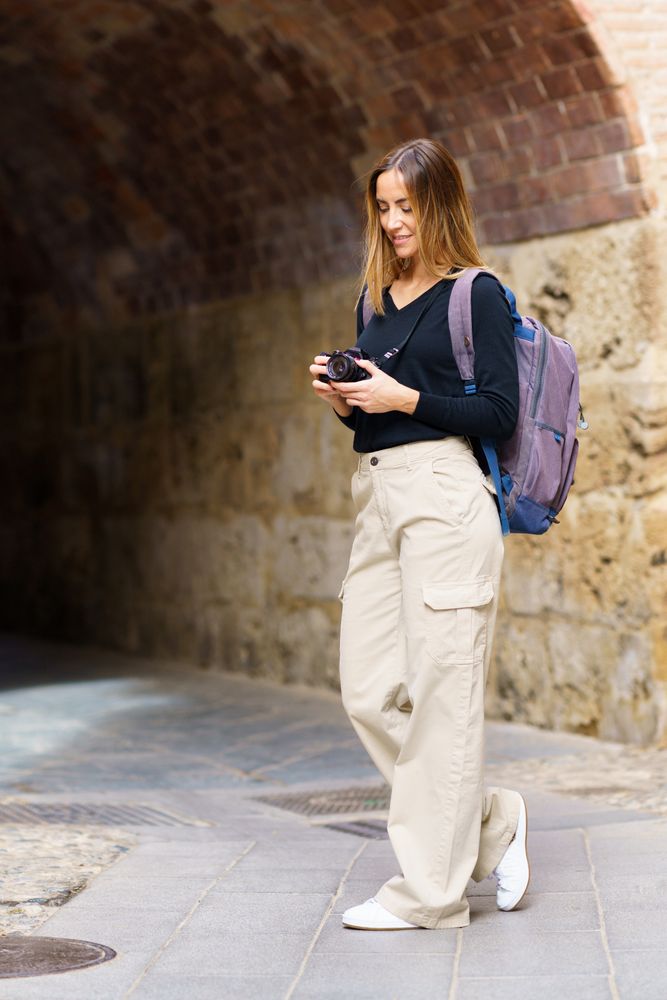 Woman checking camera near arched passage in old town