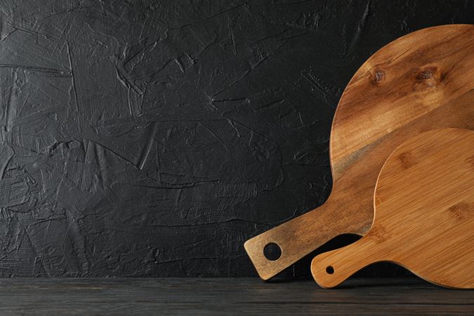 Cutting boards on wooden table against dark background, space for text