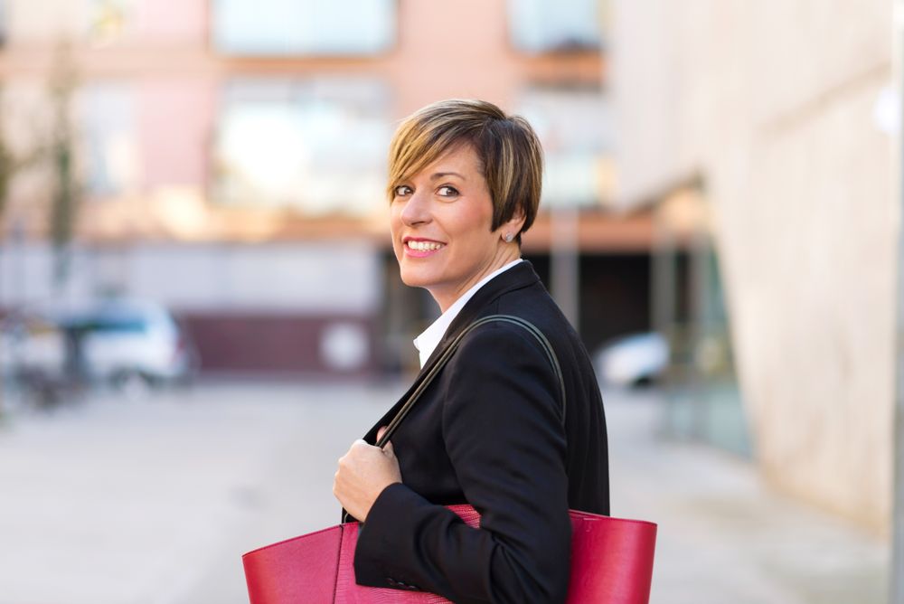 Smiling woman turning around outside holding large red hand bag