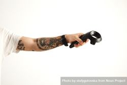 Tattooed hand holds VR remote controller 49AKm4
