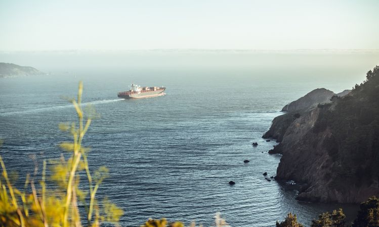 Ship floating on water near coast in sunny day