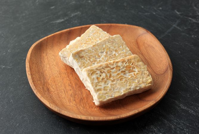 Slices of fresh tempeh on wooden plate