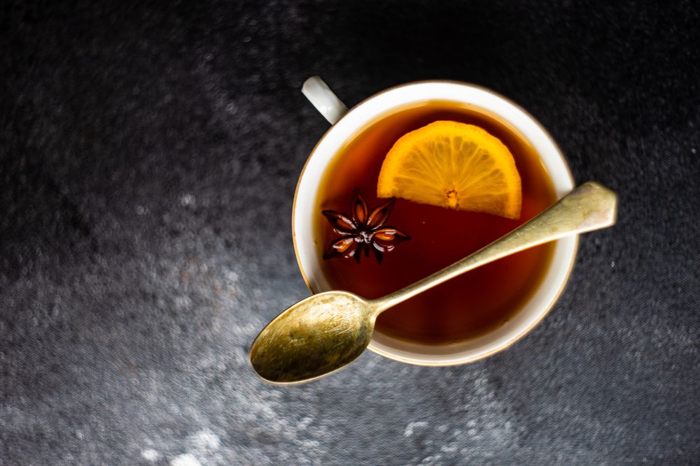 Top view of tea served in cup and saucer with lemon slice & star anise
