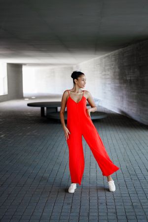Elegant dance pose in a dynamic urban setting, featuring a vibrant red jumpsuit
