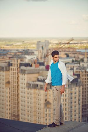 Man balances on ledge of roof and looks back