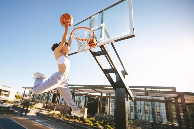 Woman basketball player slam dunking on street court